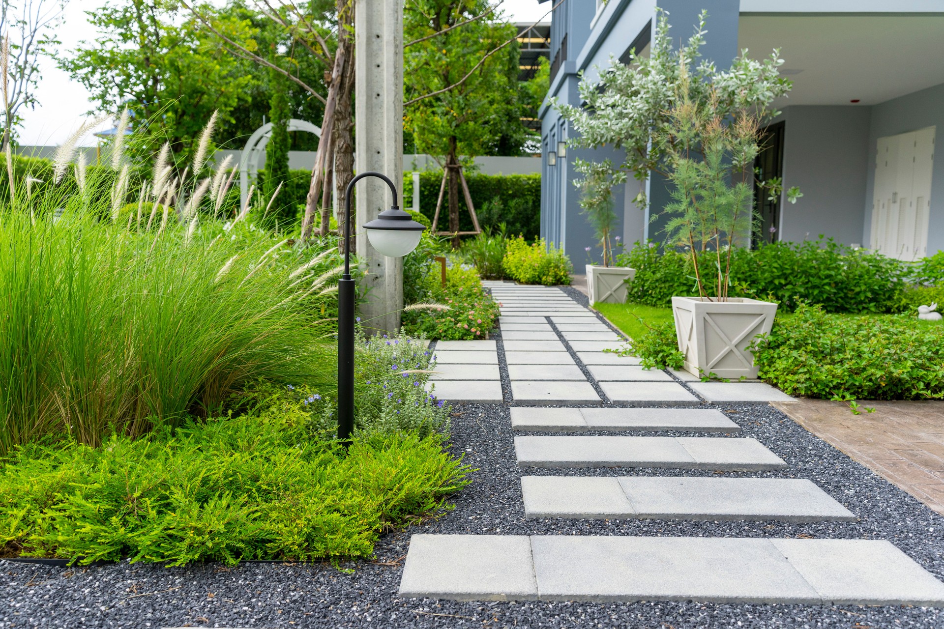 Flower garden and green plant with brick border and pedestrian pathway.